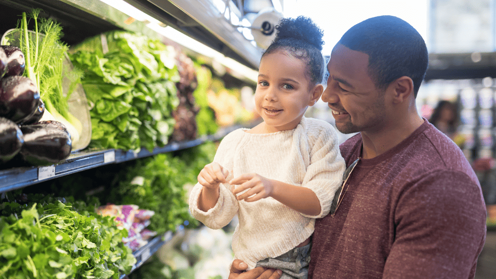 Dad and daughter food shopping together for vegetables