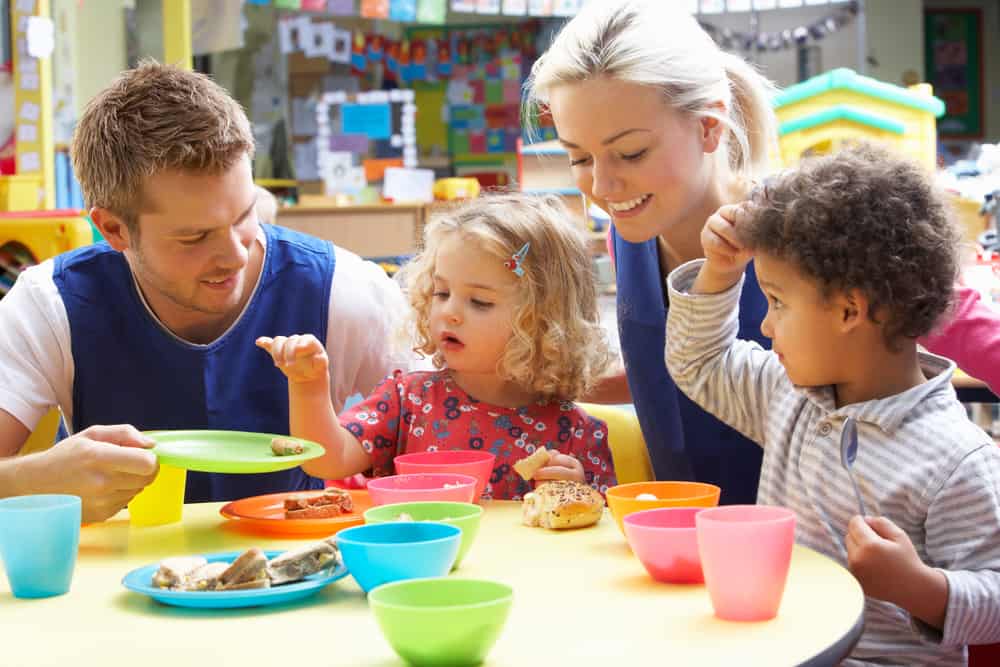 Nursery staff with children at lunchtime