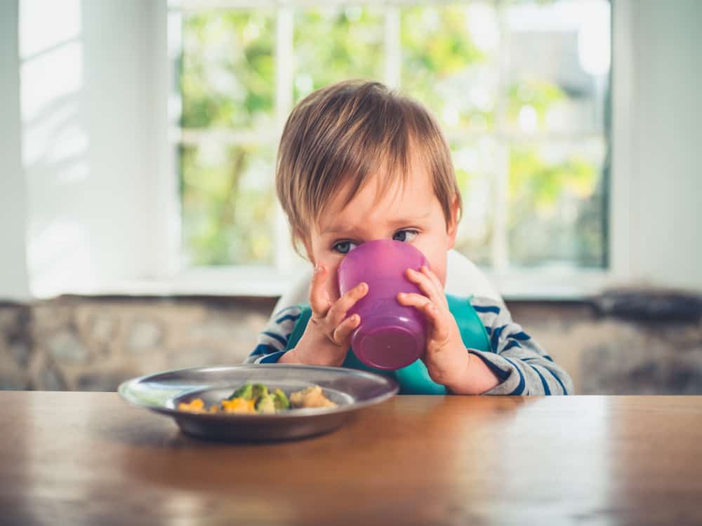 A child drinking from an open top cup