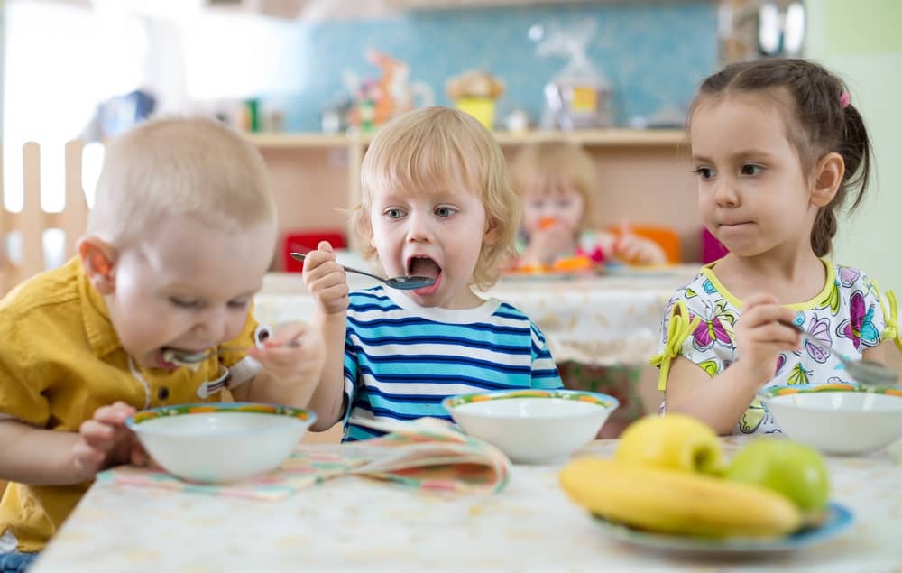 Three children sitting at a table eating together