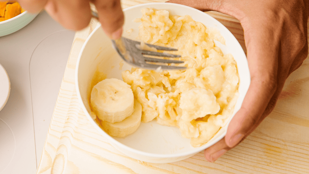 Parent mashing banana for their baby