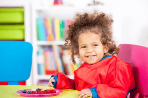 Toddler enjoying a plate of chopped fruit