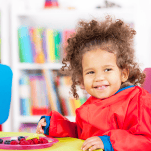 Toddler enjoying a plate of chopped fruit