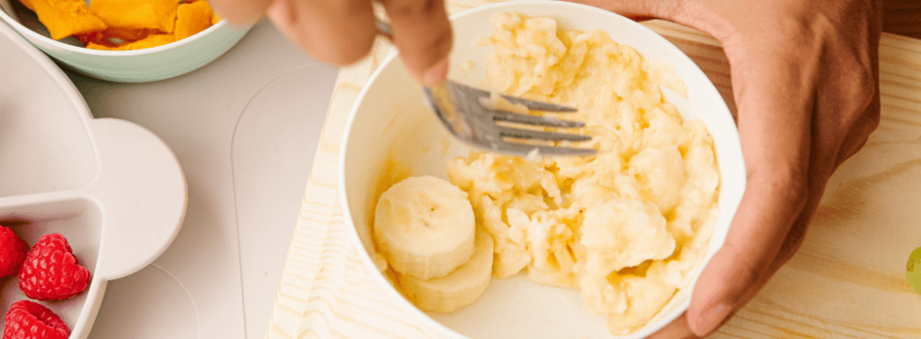 Parent mashing banana for their baby