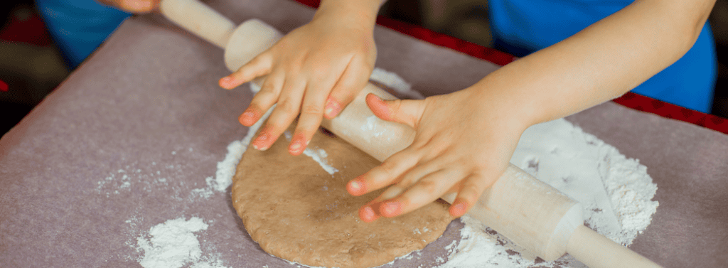 Child rolling out dough using a rolling pin
