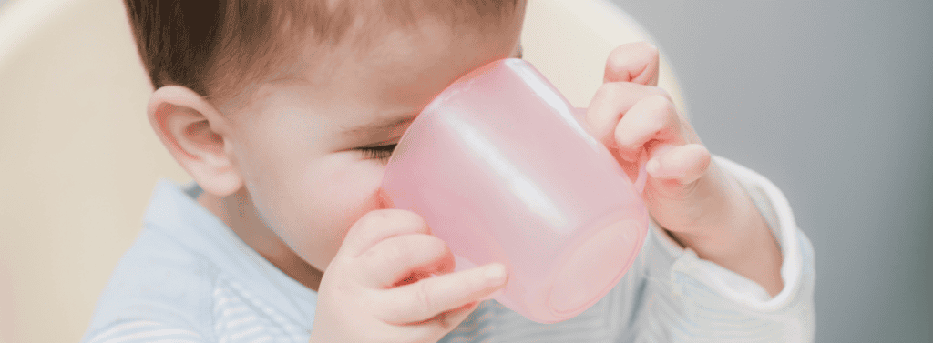 Children drinking from an open top pink cup