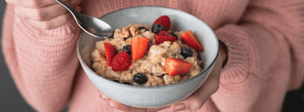 Pregnant woman eating a bowl of wheat bisks and fruit