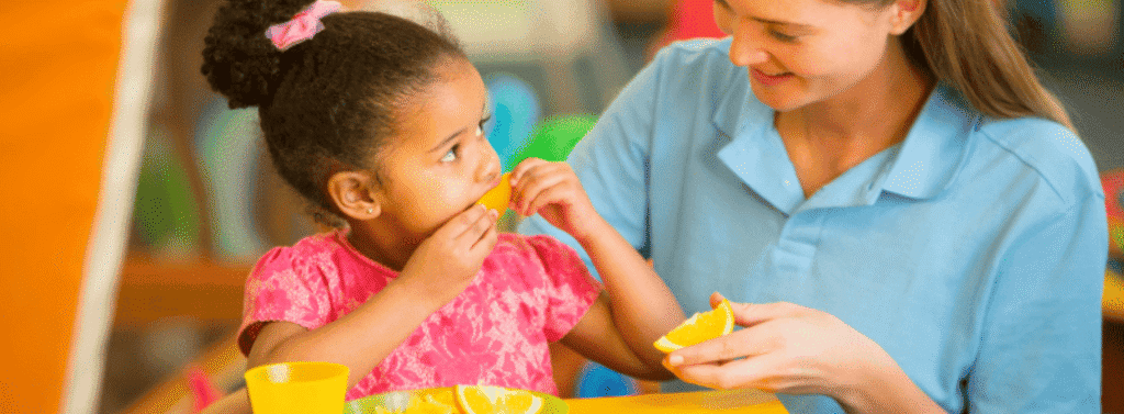 Nursery Practitioners sat with a child at snacktime