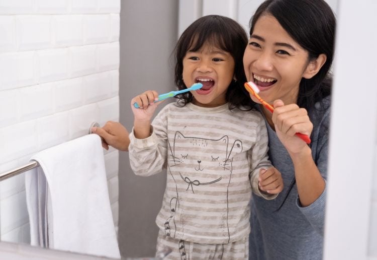 Mum and child brushing teeth together