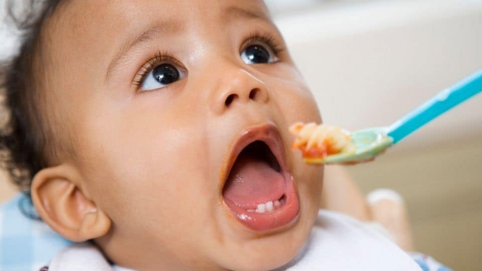 Baby boy eating pasta off a spoon